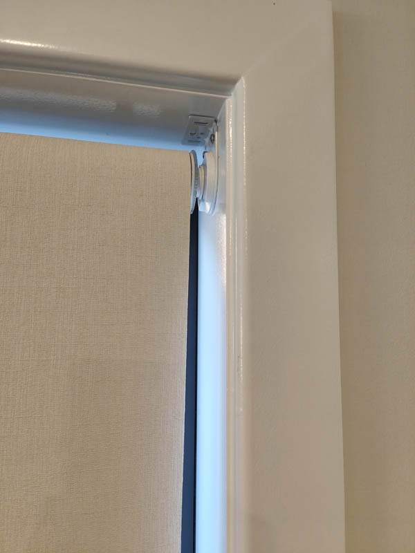 Close-up of a roller blind bracket and fabric edge in the window reveal