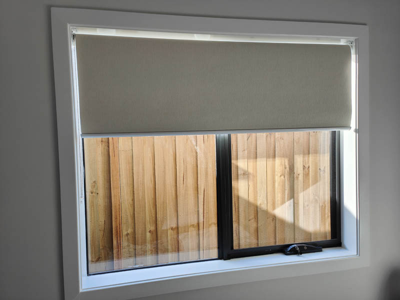 Block-out roller blind drawn halfway down a bedroom window
